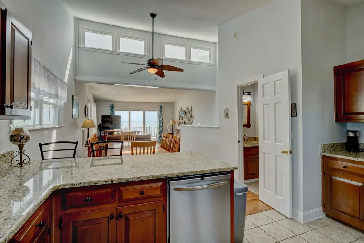 A bright, inviting kitchen island with granite countertops that opens into a cozy living area. Sunlight streams through the windows, hinting at morning breakfasts or cozy evenings spent indoors with loved ones.